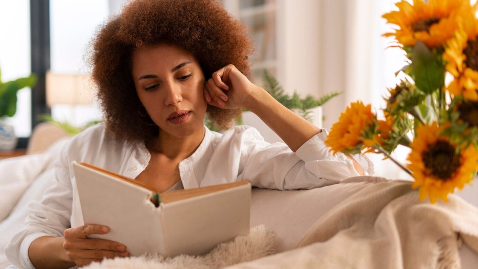woman sitting on a couch reading a book 